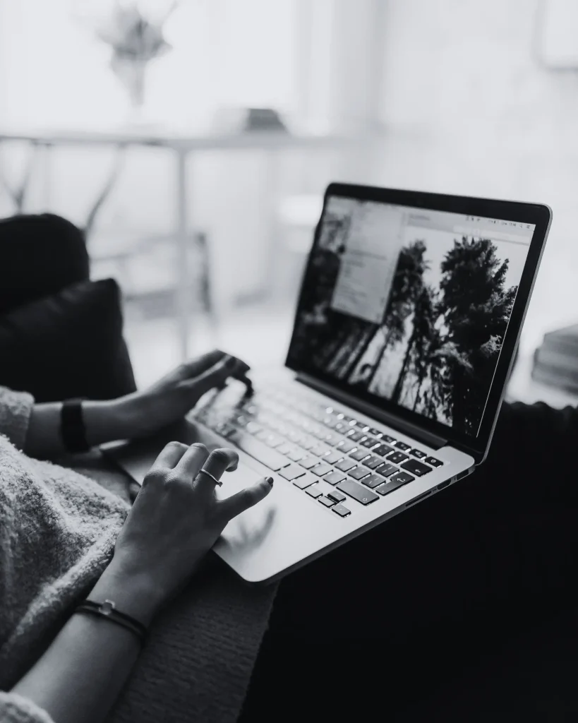 Giovane donna seduta sul divano che lavora al computer portatile