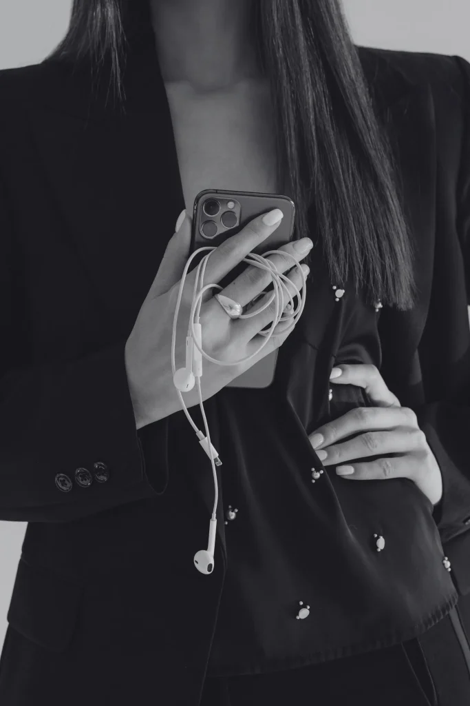 Imprenditrice in tailleur nero che controlla i social sullo smartphone